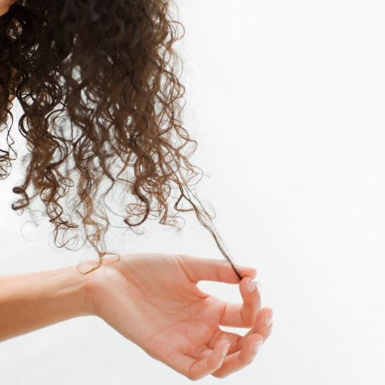 Chica estira las puntas de sus rizos para mostrar la diferencia en definicion 